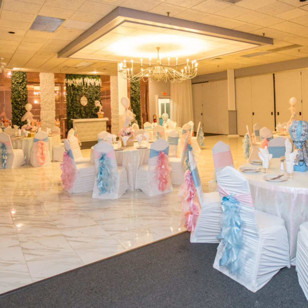 Intimate Emerald Ballroom set up for a baby shower with pastel pink and blue chair sashes and elegant chandeliers.